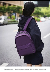 Outdoor street view of a purple nylon backpack with black UMUJIA lettering on the front