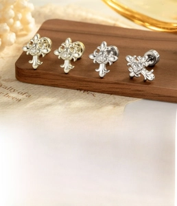 Macro detail of vintage cross cartilage earring in coffee gold steel with zircon stones