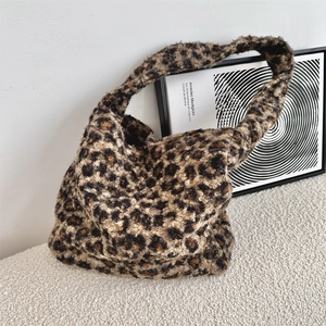 Detailed texture of leopard print faux shearling tote bag on a white textured sofa