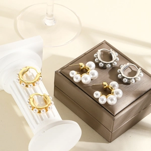 Macro shot of gold and silver C-shaped earrings with gradient white pearls