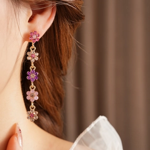 Close-up of pink and purple floral tassel earrings with sparkling rhinestones on model