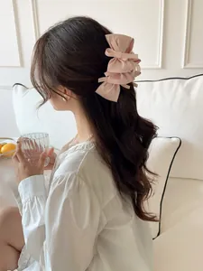 Detail of pink satin multi-layer bow hair claw clip worn on model's head