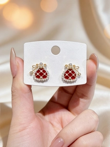 Close-up of gold-plated lucky bag stud earrings with red enamel and sparkling cubic zirconia