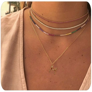 Colliers tennis en zircon coloré et pendentif lettre M doré portés par un mannequin