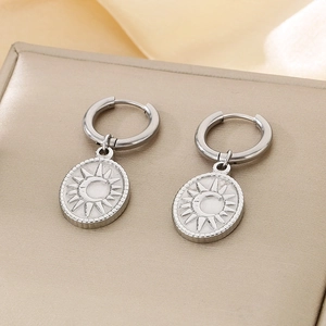 Detail of silver sun and moon oval pendant earrings in stainless steel on textured surface