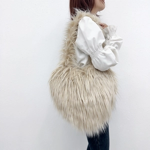 Detail of fluffy beige faux fur heart tote bag paired with a white puff sleeve top