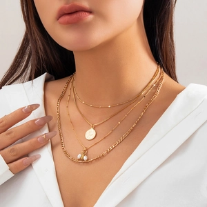 Detail of layered gold necklaces with imitation pearls and vintage coin pendants