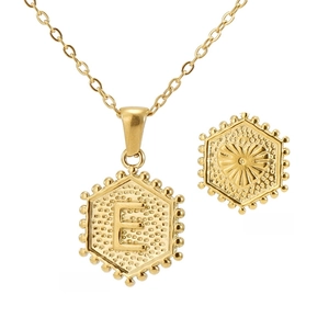 Detail of 18K gold hexagonal necklace showing letter E and heart relief on back