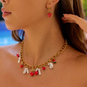 Fashion model wearing gold jewelry set with strawberry, cherry, and pearl pendants