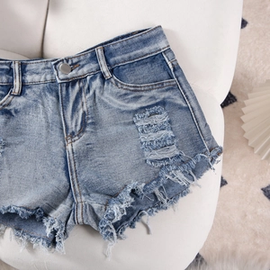 Detail shot of distressed denim shorts showing frayed hems and ripped texture accents