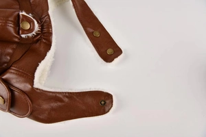 Macro detail of brown faux leather texture and white fleece lining with metal buckle