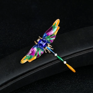 Vintage enamel dragonfly brooch with colorful wings and a centered blue gemstone