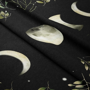 Close-up of the moon phase and green leaf print on black bohemian tapestry fabric
