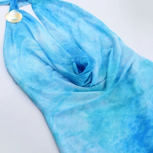Detail of the blue tie-dye halter neck dress featuring a metallic shell decorative buckle