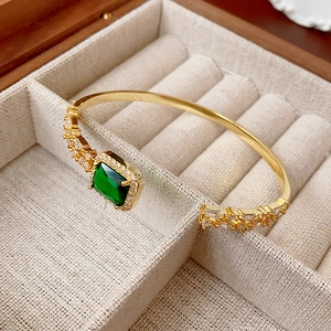 Macro shot of gold emerald bangle featuring micro-pave cubic zirconia on linen background