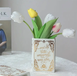 Detail of book-shaped white ceramic vase with gold text and colorful tulips decor