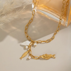 Detailed shot of golden fish and shell pendants with freshwater pearls on a gold chain
