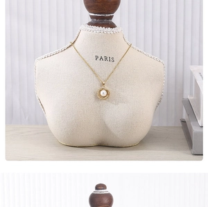 Detail showing a gold pearl pendant necklace on a minimalist mannequin display stand