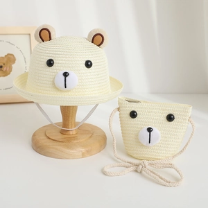 Close-up of cream straw hat and matching bear face shoulder bag for children