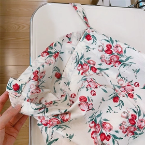 Close-up of soft floral cotton fabric featuring red tulips and green leaves pattern