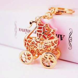 Golden swan stroller keychain with rhinestones and cat eye stone on a pink book