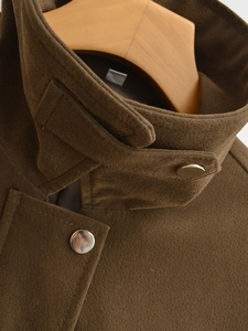 Detail der kaffeebraunen Wildlederjacke mit Stehkragen und glänzenden silbernen Metallknöpfen