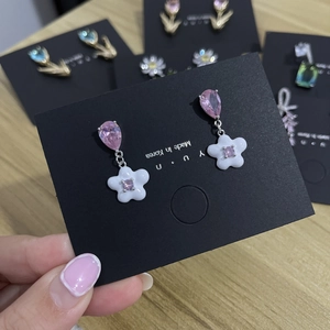 Detail of pink teardrop crystal earrings with white flower charms on a display card