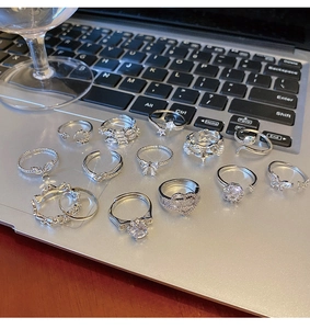 Set of 13 silver rings with rhinestones and butterflies displayed on a laptop