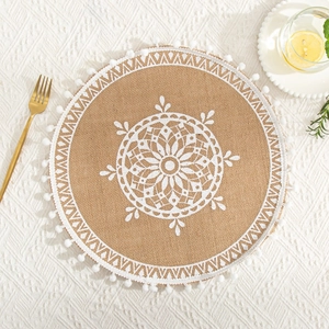 Close-up of a jute placemat with white lace pattern and decorative tassel fringe