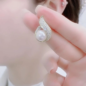 Close-up of pearl stud earring with curved gold setting and pavé white zircon stones