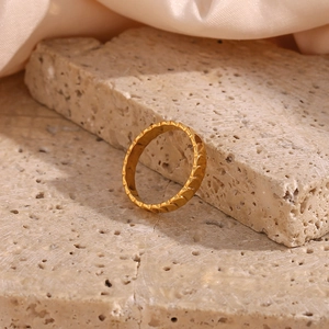 Detailed view of an 18K gold-plated ring with fish scale texture on a beige stone