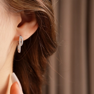 Close-up of elegant double circle silver earrings with small zircons on female model