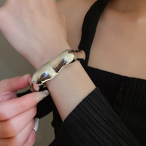 Detail shot of irregular silver liquid metal bangle with a polished mirror finish on wrist