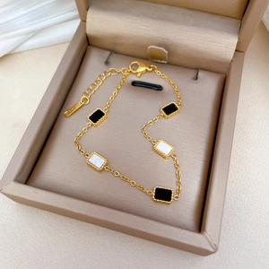 Elegant gold titanium steel bracelet with black and white rectangular pendants in jewelry box