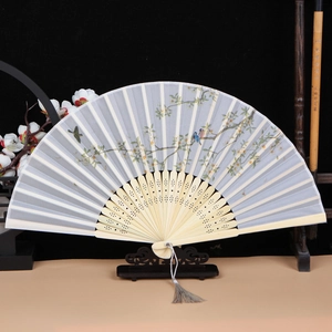 Exquisite detail of a folding fan with floral bird patterns on a bamboo frame with tassel