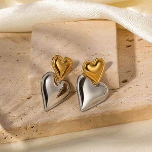 Detail of two-tone heart earrings in gold and silver finish on a luxury stone base