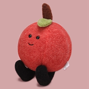 Detail of red apple plush toy showing the soft grainy fabric texture and leaf stem