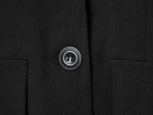 Close-up of a black blazer featuring twill fabric texture and classic four-hole button detail