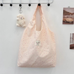 Gros plan sur un sac cabas floral avec motifs lapins et étiquette en tissu tissé