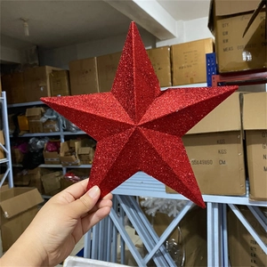 Close-up of a 3D red glitter star tree topper held to show textured surface and size