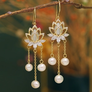 Detail of gold lotus tassel earrings with white opal and dangling pearls on a branch