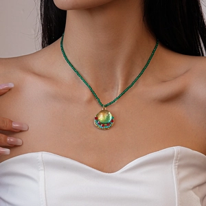 Detail of vintage bohemian necklace with green beads and multicolor stone pendant on model
