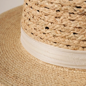 Handwoven raffia flat top hat for women featuring delicate hollow texture and ribbon trim