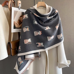 Close-up of a dark grey cat print scarf with tassel edges on a white wool coat