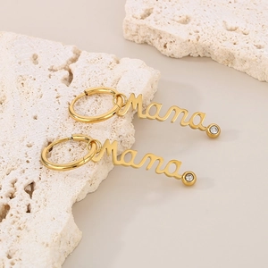 Close-up of golden Mama letter hoop earrings with sparkling cubic zirconia on stone base