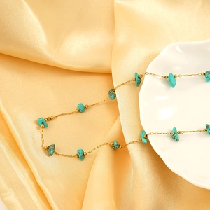 Bohemian gold chain necklace featuring turquoise stones and glazed beads on satin background