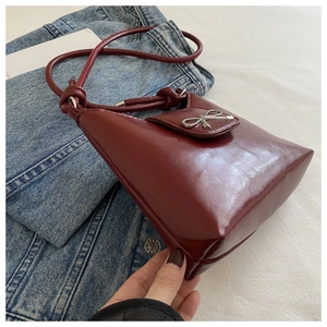 Close-up of wine red faux leather bag featuring a silver metal bow buckle and sleek side