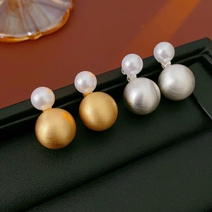 Detail of silver needle pearl earrings with gold and silver brushed metal spheres