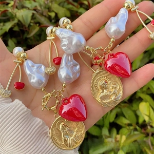 Detail of baroque pearl necklace with heart, cherry charms and gold religious coin