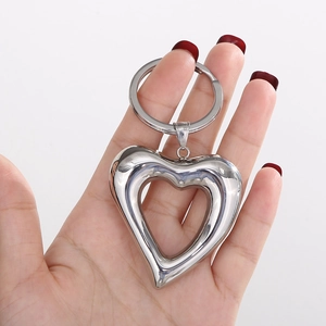 Polished silver heart-shaped hollow keychain pendant held in hand for accessory display